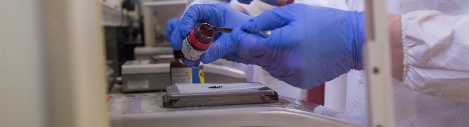 威尼斯赌场网站化学系的学生在实验室里戴着手套从罐子里取出材料.